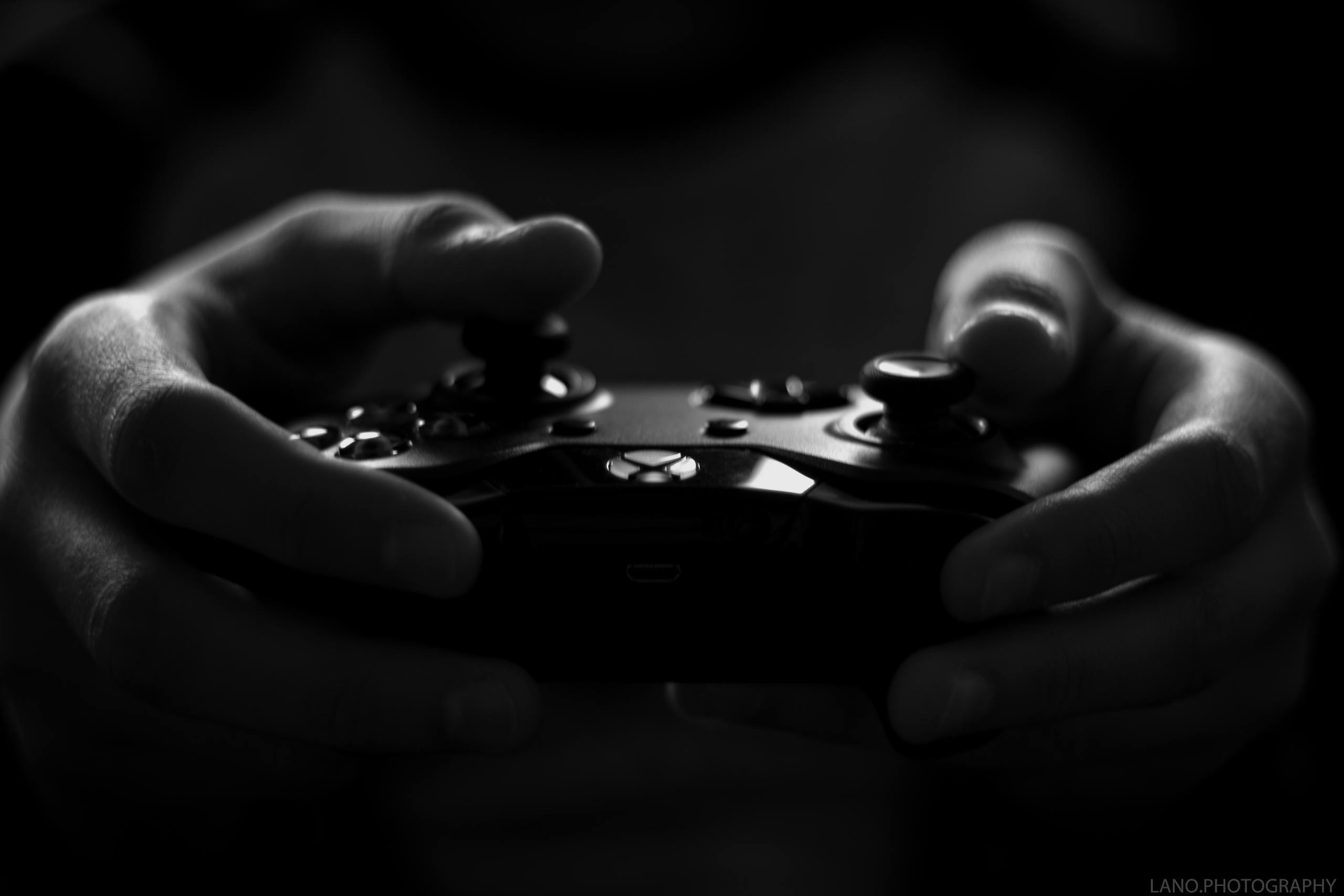 Close-up of hands holding a game controller in a monochrome setting, capturing the essence of gaming.
